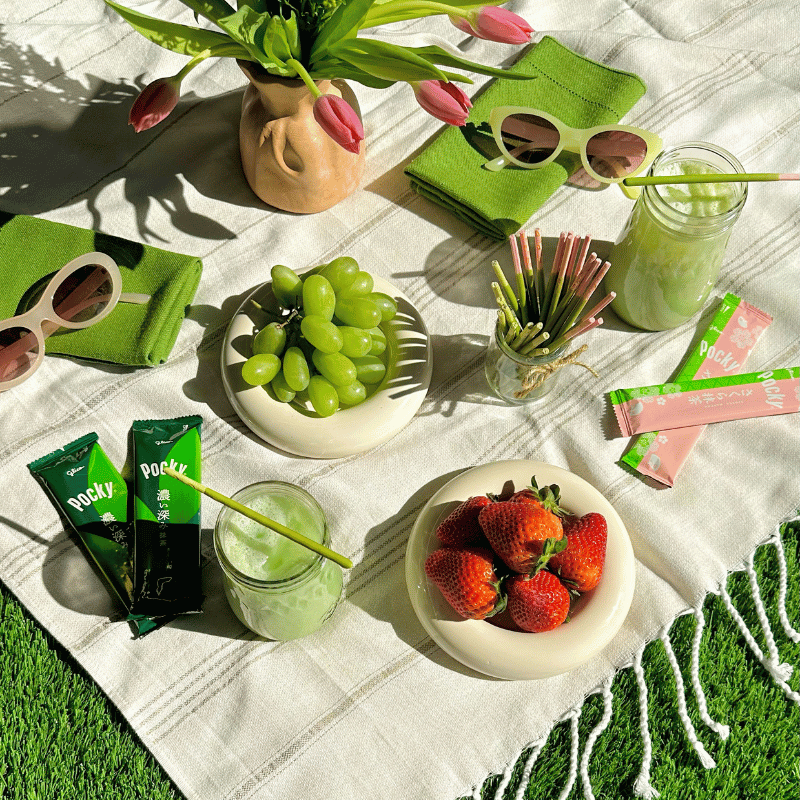 Outdoor picnic setup with fruits, matcha latte, and snacks, including Pocky Double Rich Matcha and Cherry Blossom Matcha