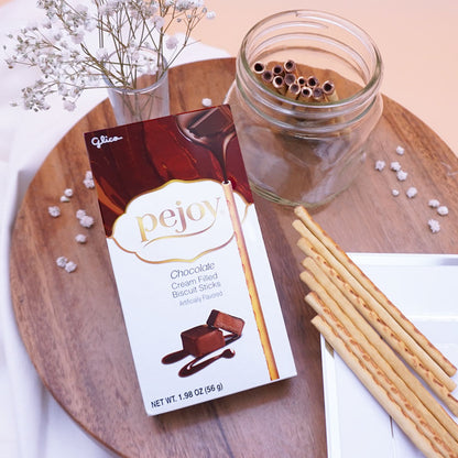 Box of Pejoy Chocolate on a wooden board with a jar and plate of Pejoy Chocolate sticks. 